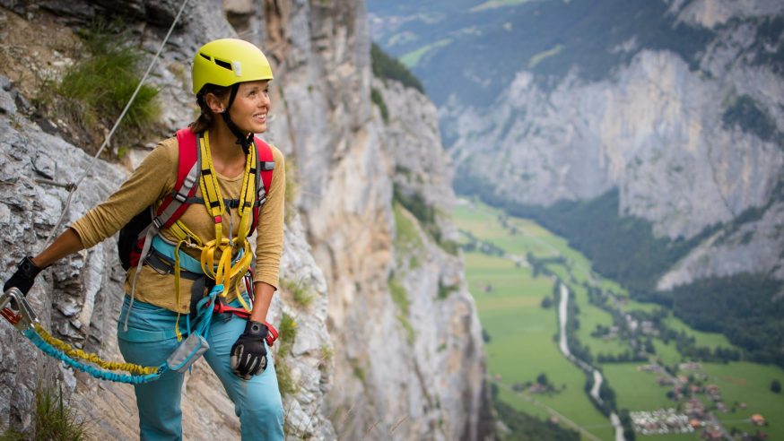 Young, male climber on a via ferrata route - climbing on a rock in Swiss Alps